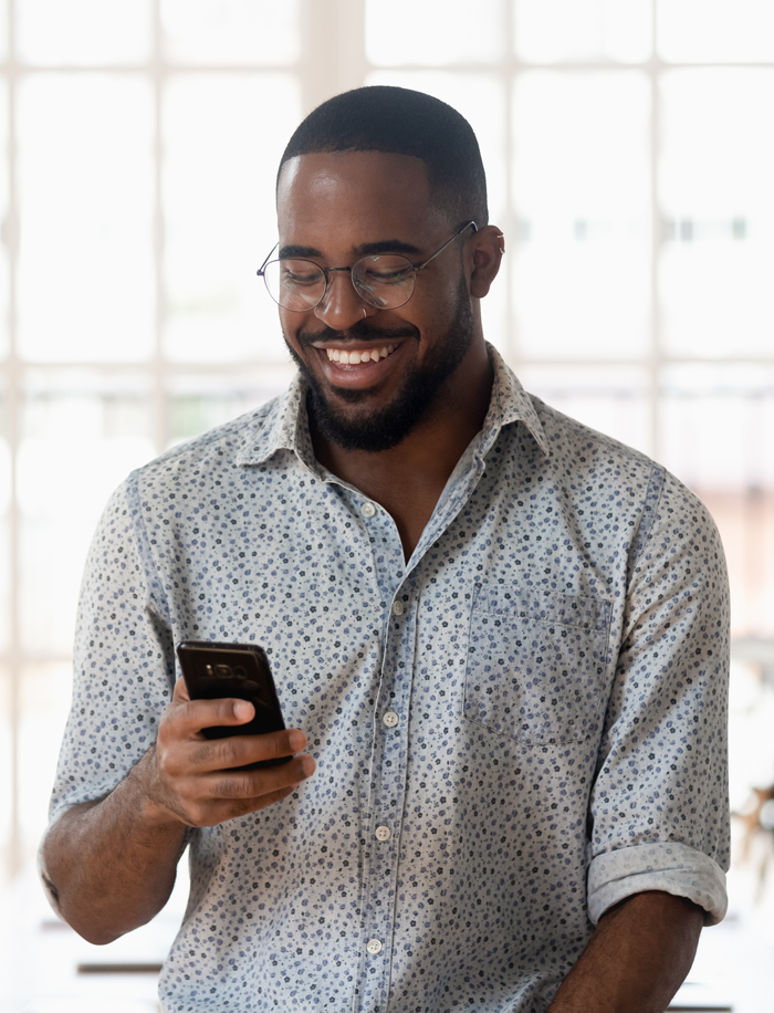 A man smiles down at his phone as he contacts a Utilities customer support center