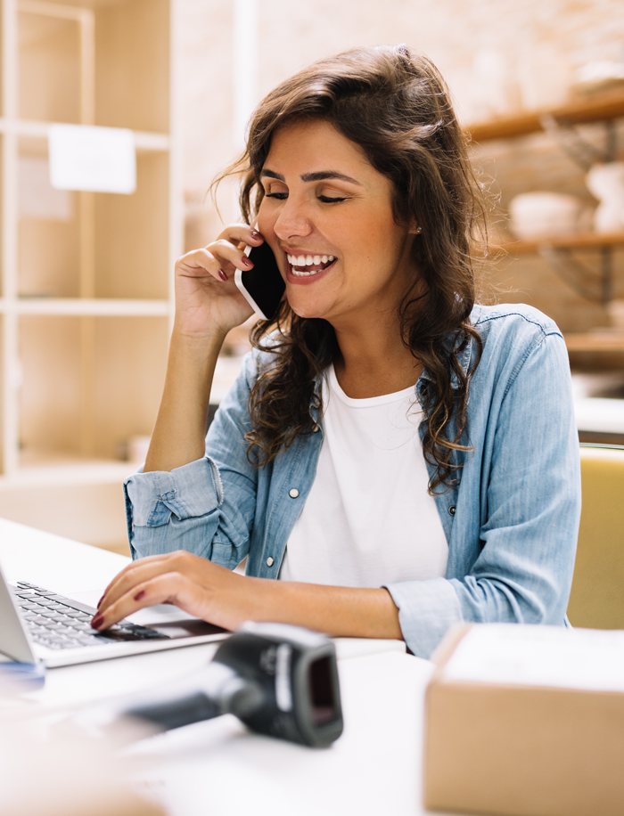 A woman is talking on the phone and looking at her laptop as she speaks to a retail customer contact center