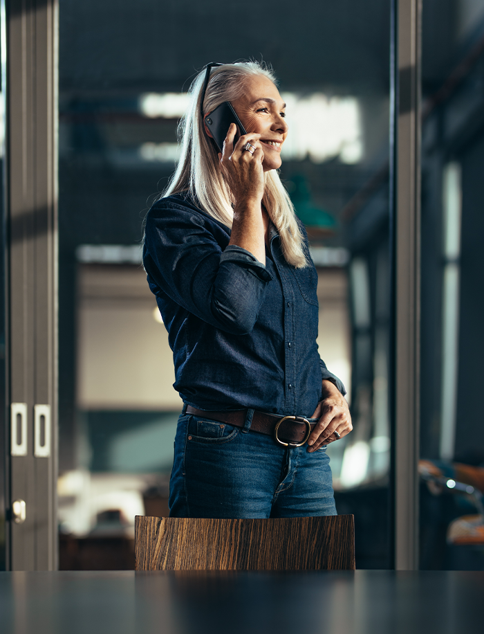 A woman is smiling as she listens to someone on her cell phone